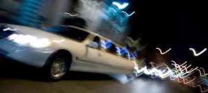 An abstract blur of a white limousine in the city at night with light trails.